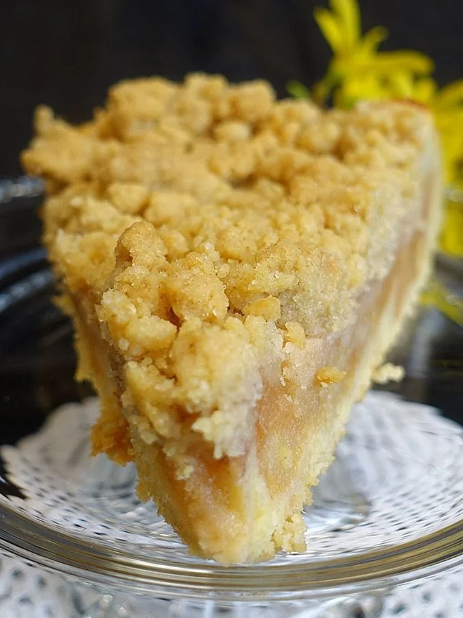 Apfelkuchen mit Streuseln auf einem Holzbrett serviert