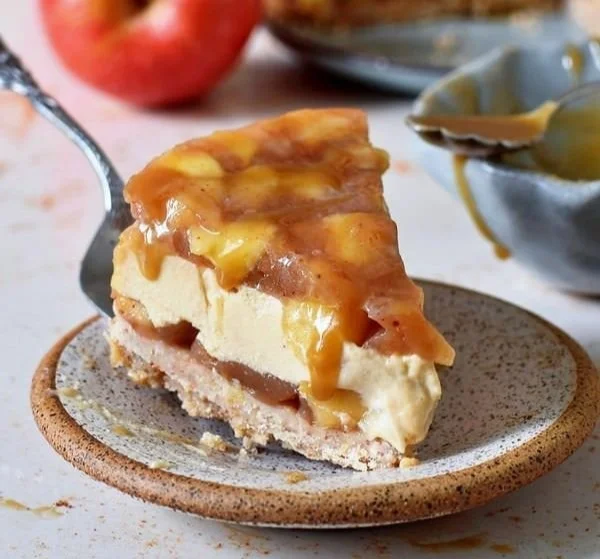 Veganer glutenfreier Karamell-Apfel-Käsekuchen auf einem rustikalen Holzbrett.
