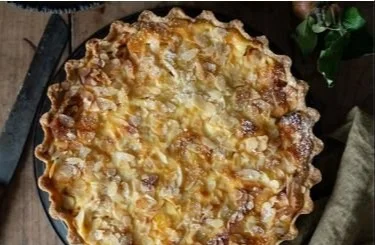 Cremige Apfel-Schmandtarte mit Mandeln in einem weißen Teller