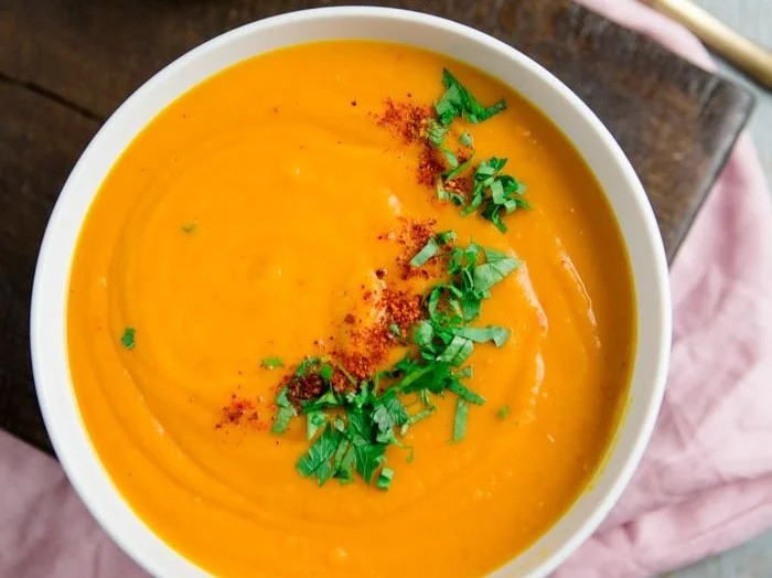 Schüssel mit Thai Curry-Kürbissuppe, garniert mit frischen Kräutern